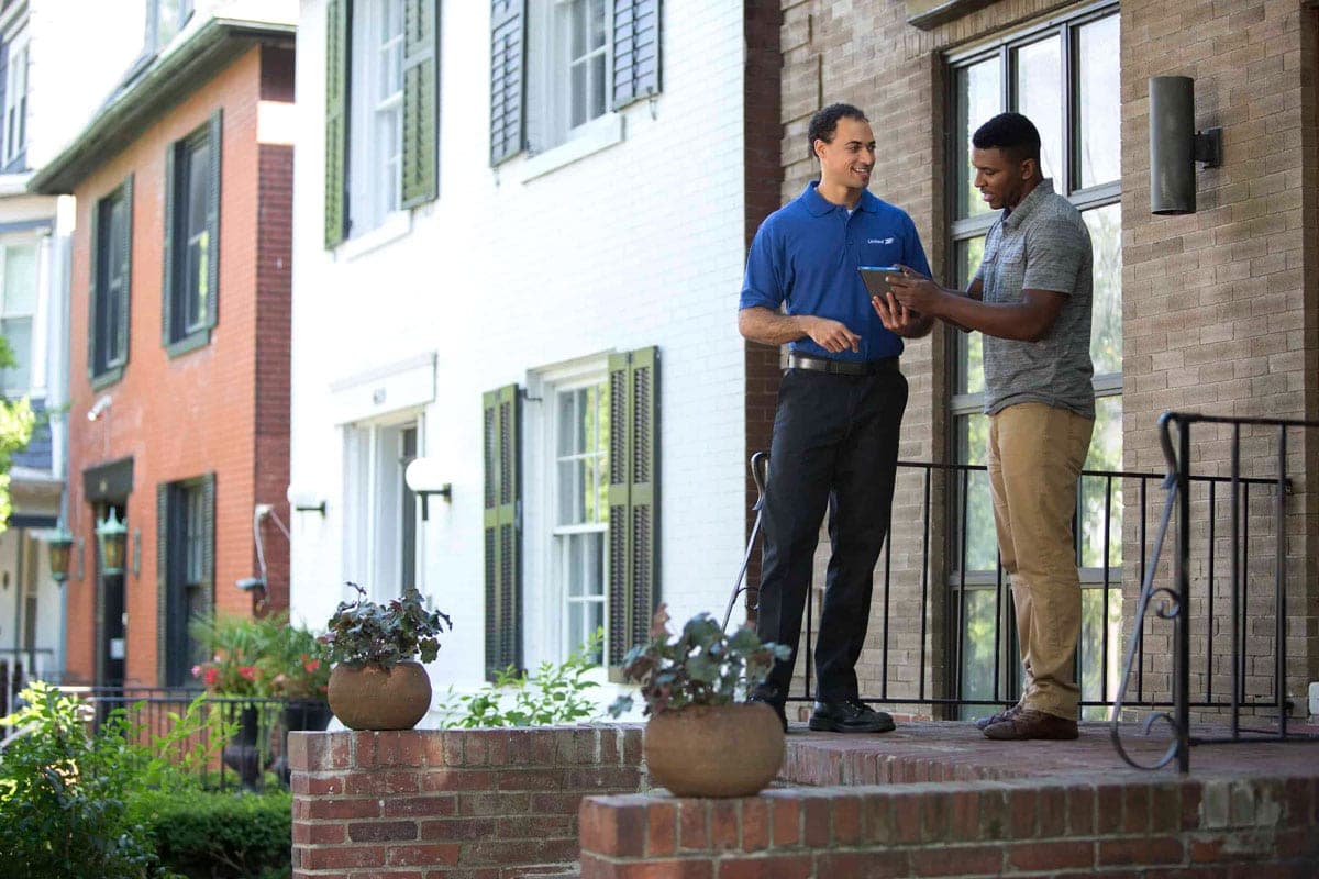 united van lines mover meets man in front of his home to discuss the bill of lading.